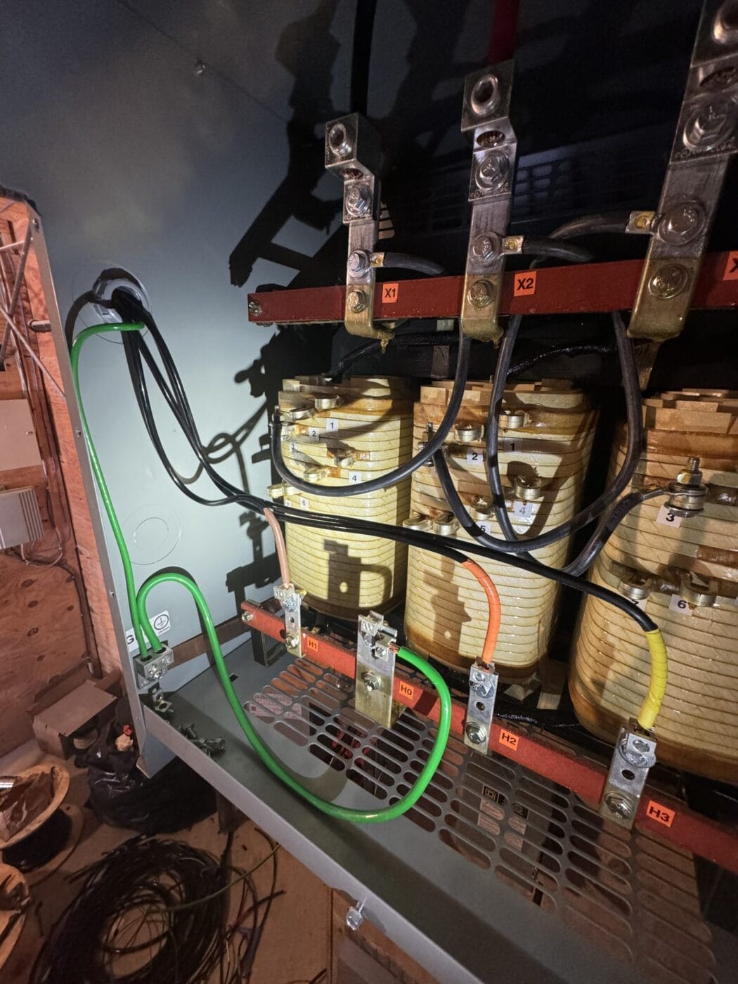 Electrical wiring and coils inside a transformer cabinet with labeled connections and various cables.